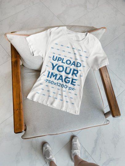 Mockup of a Bella Canvas T-Shirt Lying on a Chair Featuring a Woman's Legs