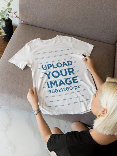 Over Shoulder Mockup Featuring a Woman Putting a Bella Canvas T-Shirt on a Couch