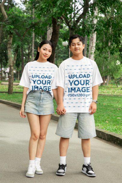 Oversized T-Shirt Mockup Featuring a Happy Man and Woman Walking Hand-in-Hand in the Park