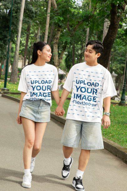 Oversized T-Shirt Mockup Featuring a Romantic Couple Holding Hands and Walking in the Park