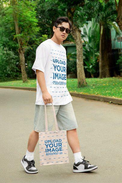 Oversized Tee Mockup Featuring a Man Walking in the Park With a Sublimated Tote Bag