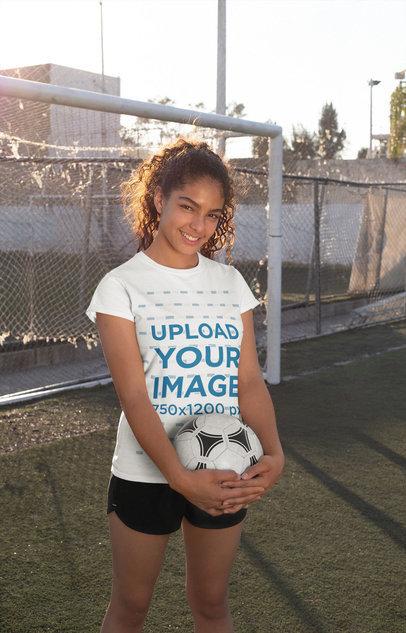 Tee Mockup of a Smiling Teenager Holding a Soccer Ball in the Field